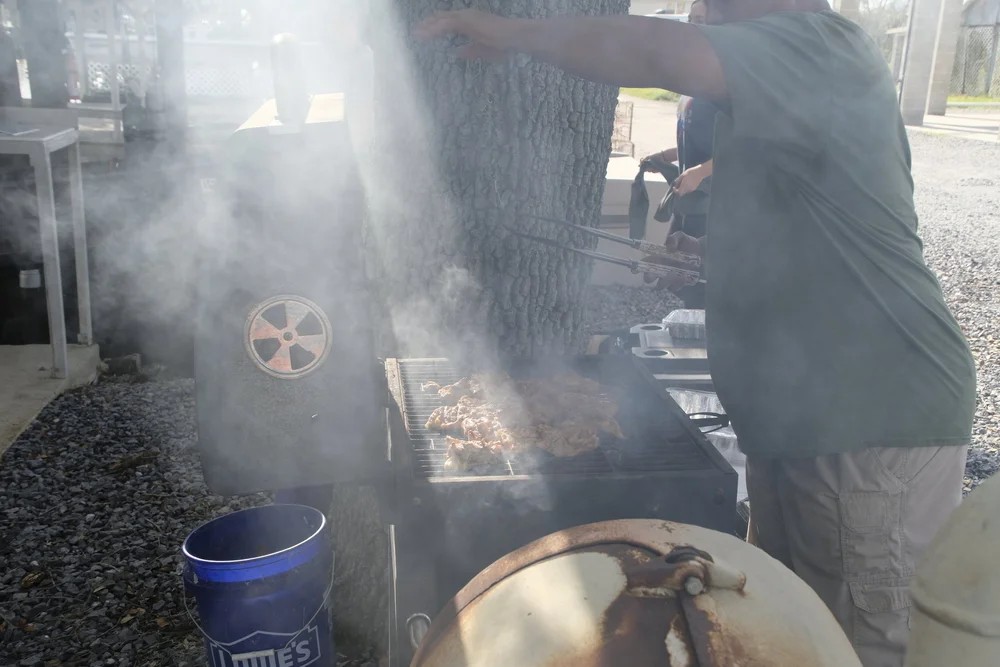 Club member tending a smoky charcoal grill at a BFF cookout event