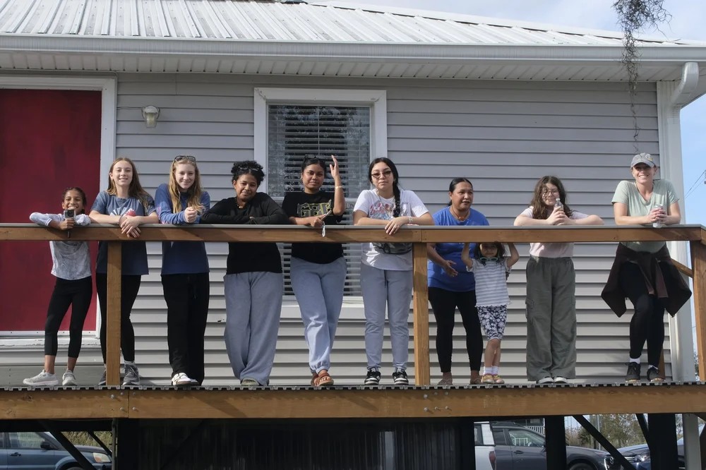 Group of girls and women posing together on a raised porch at the club property