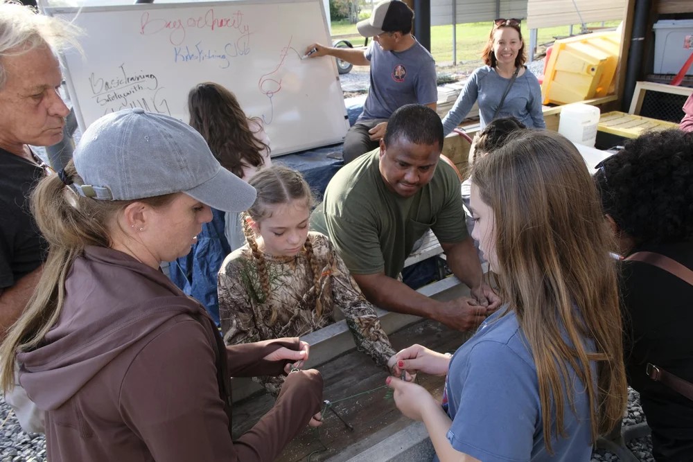 Adults and children working together on fishing knot skills at the club workshop