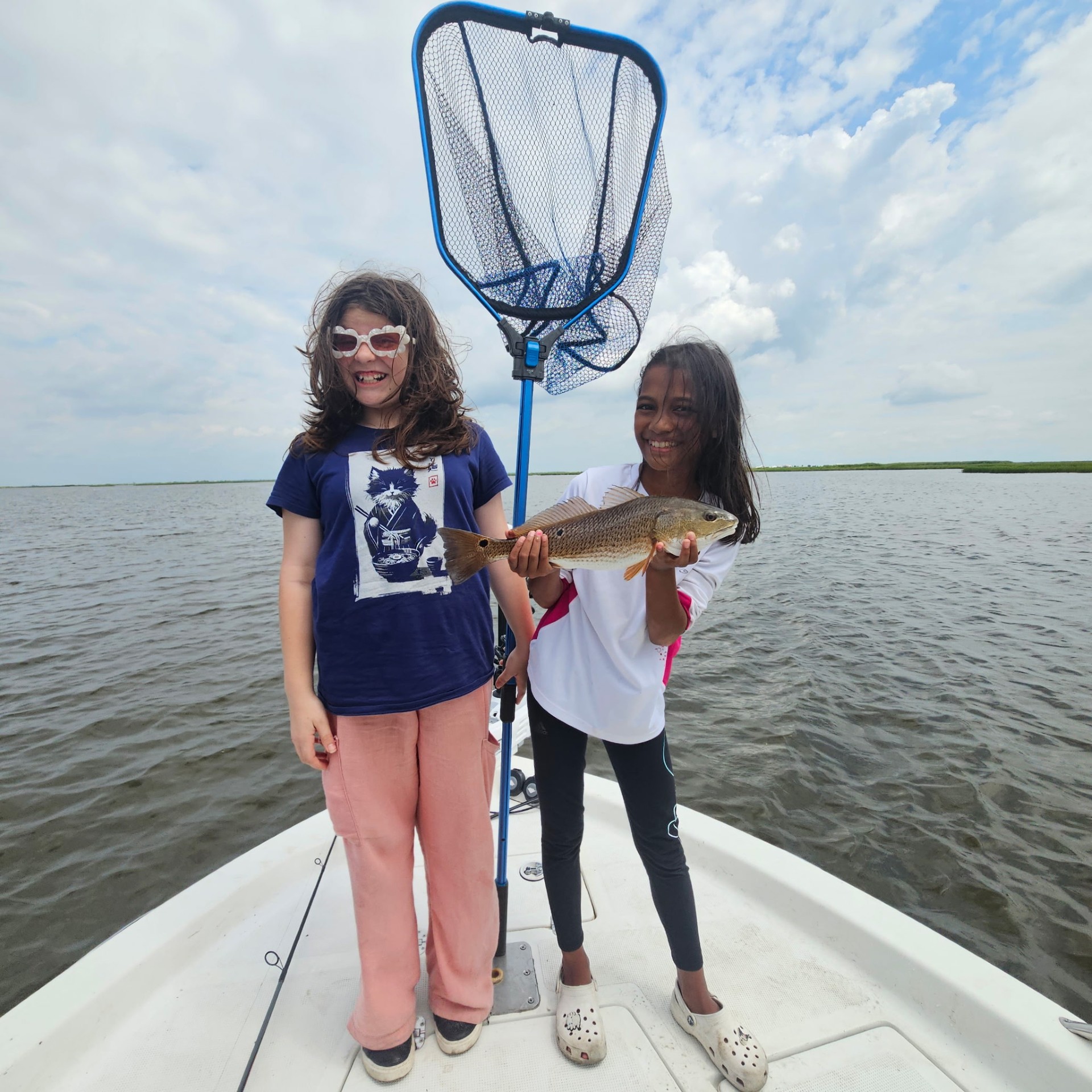 Two young BFF members proudly holding up a fish they caught together, landing net in hand