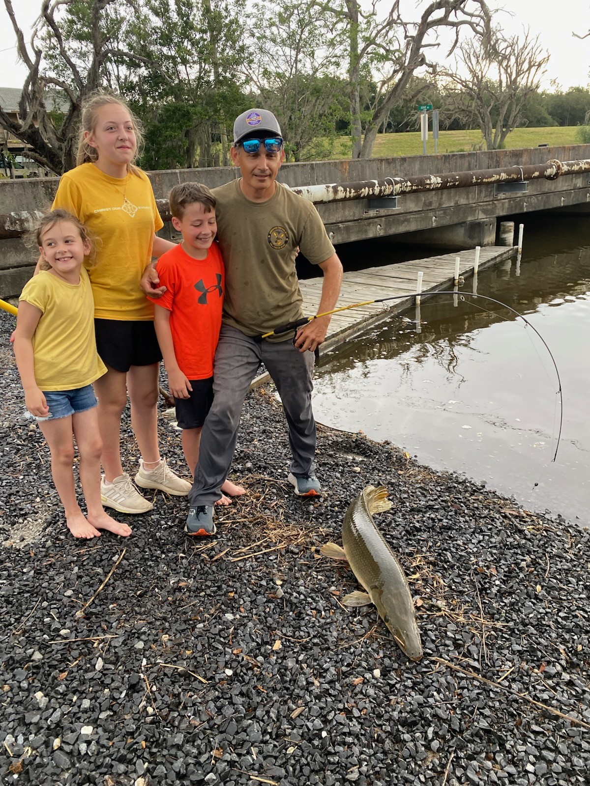 Kids and a BFF volunteer posing on the dock after a successful fishing outing