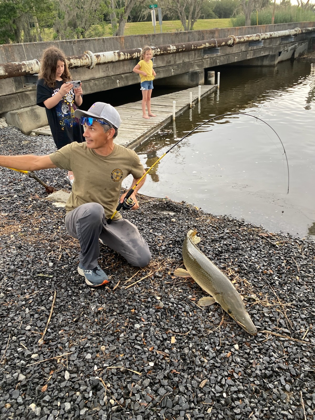 BFF member crouching on the shoreline, proudly showing off a large drum fish