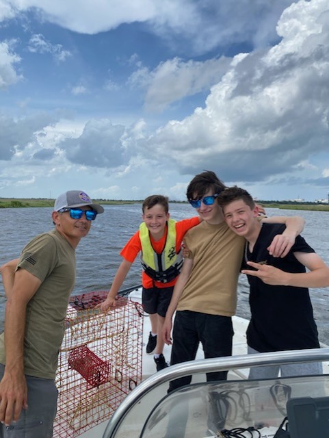 Three young BFF members grinning together out on the water for a club fishing day