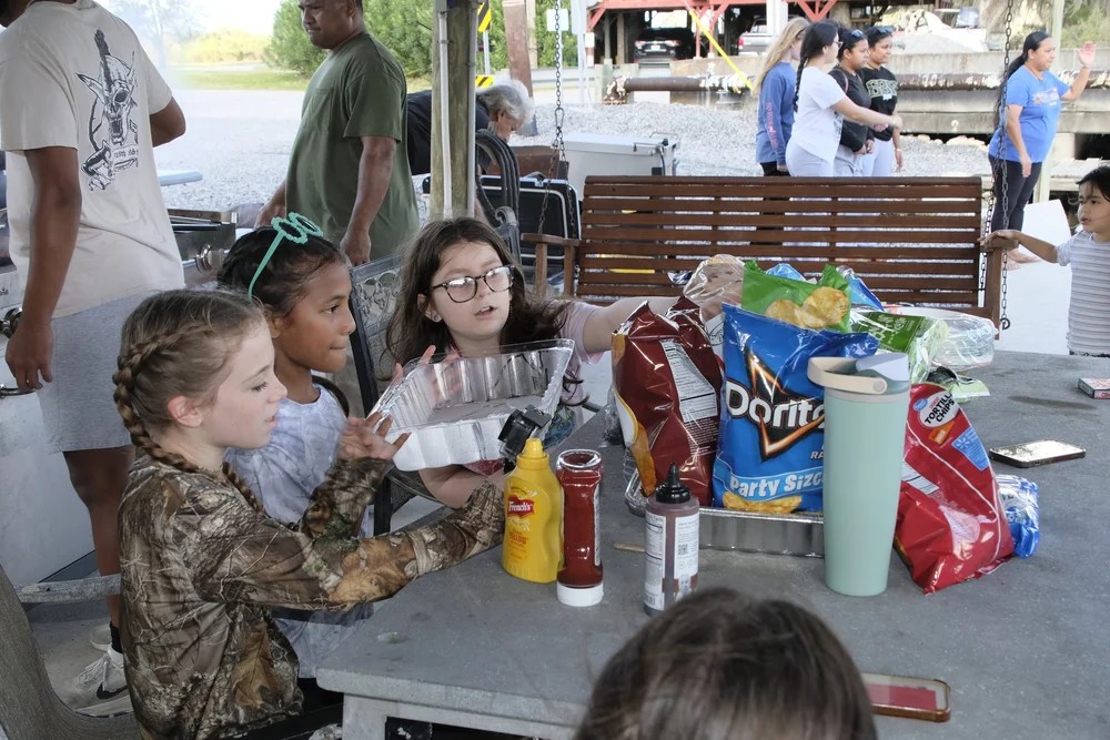 Kids gathered at a picnic table with snacks at a Bayou Family Fishing club event