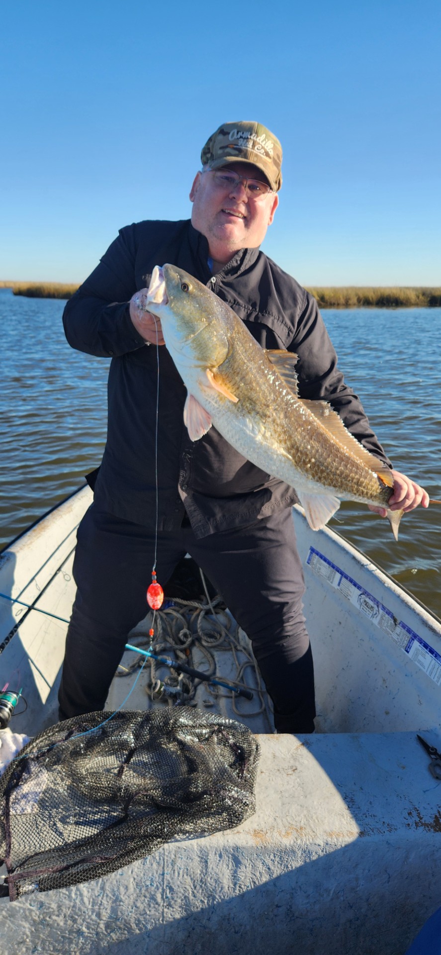 BFF member at the dock crouching next to a large black drum fish after a successful trip